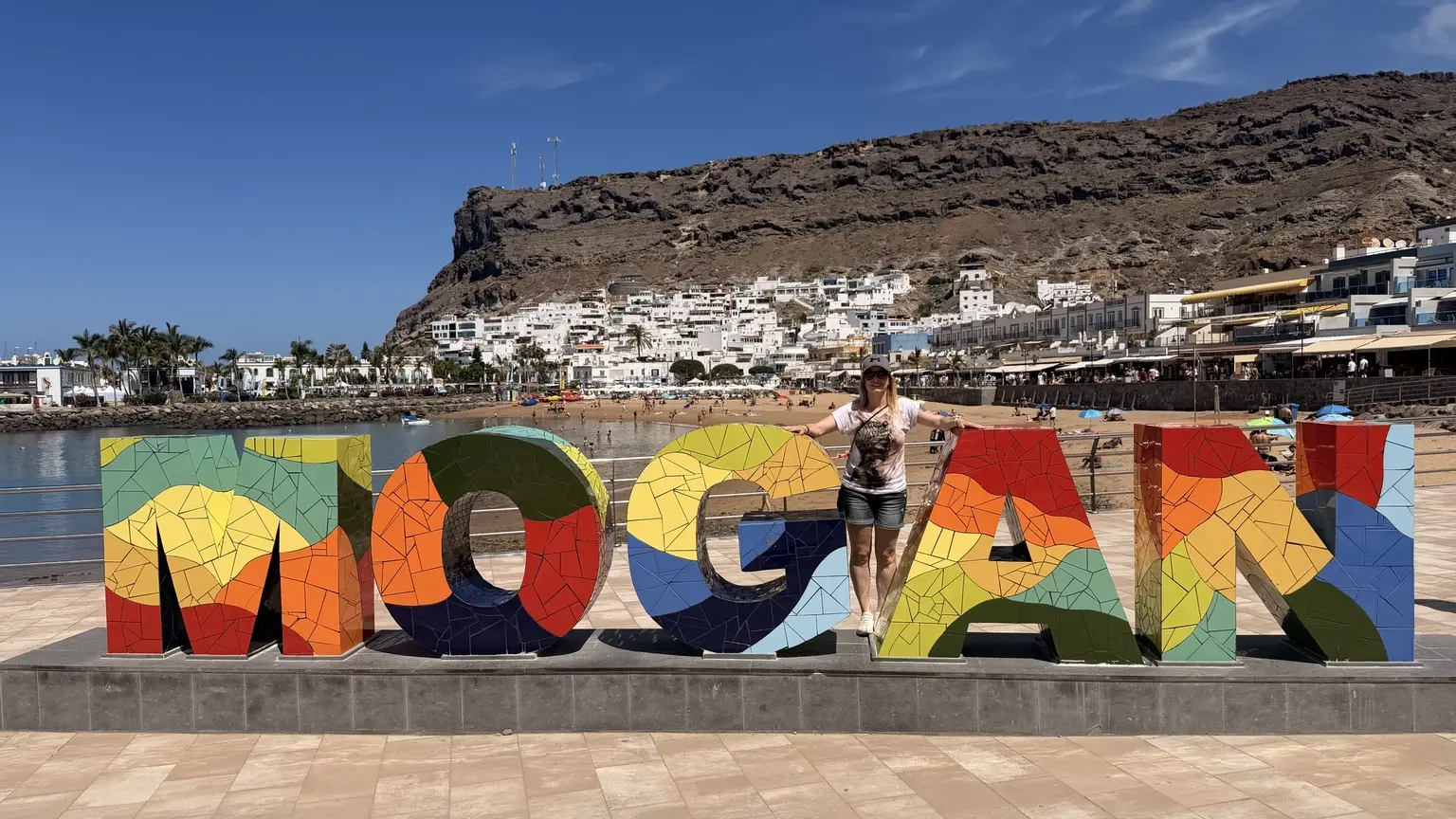Alaitz junto al letrero de Mogán frente a la playa