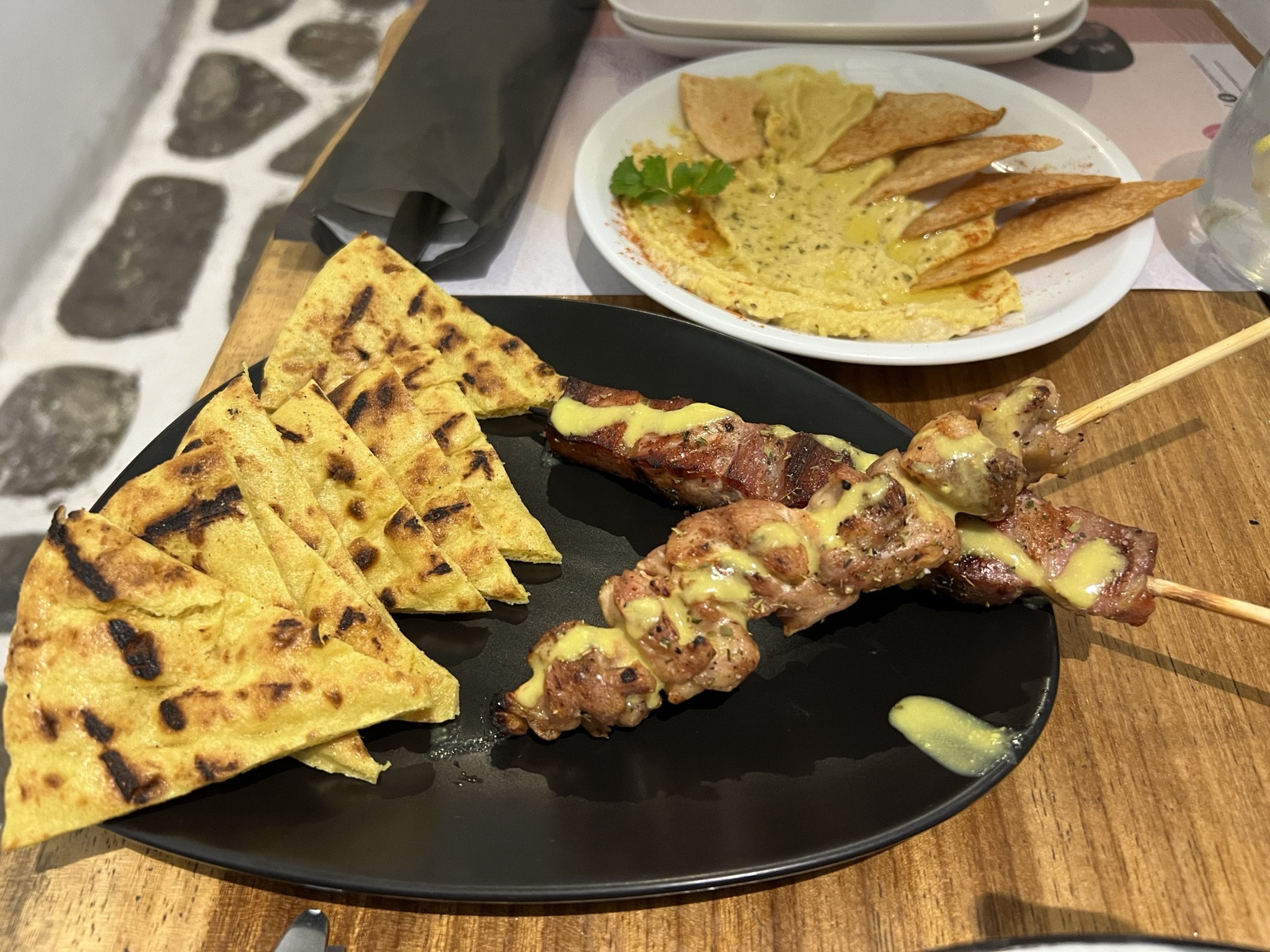 Brochetas, pan de pita y hummus en Pepper Mykonos