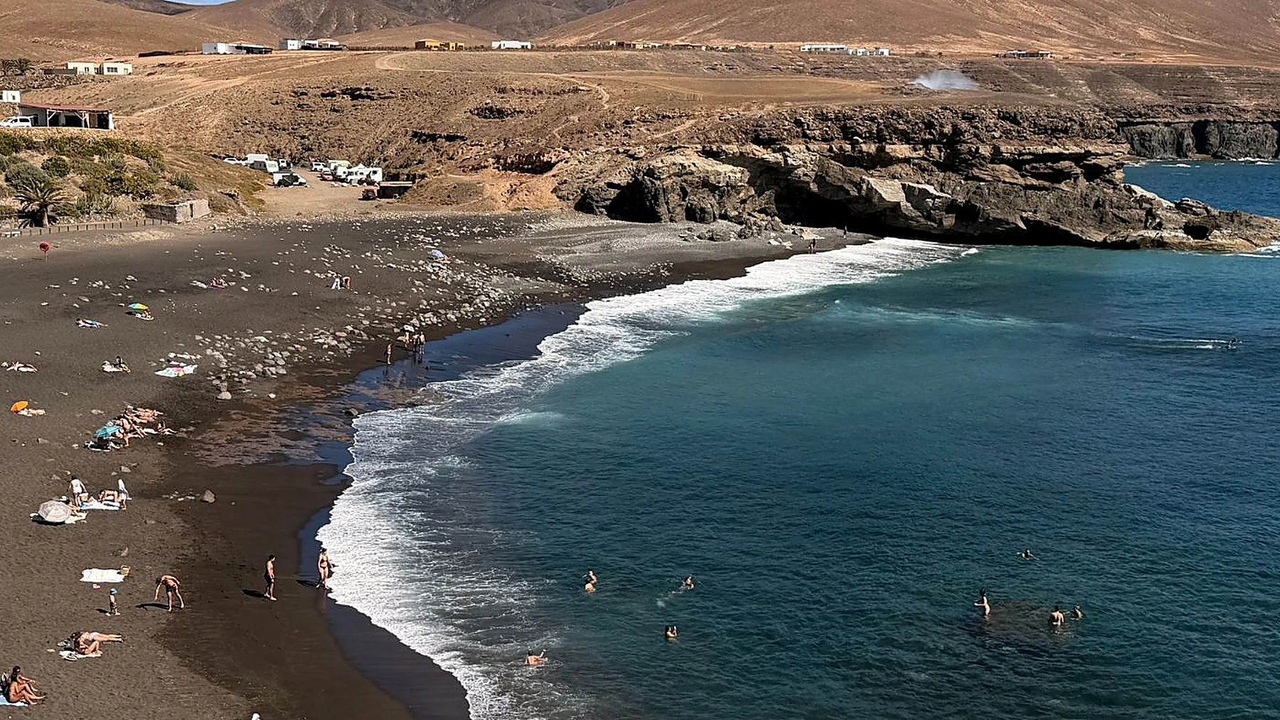 Playa de arena negra de Ajuy con el pueblo y los acantilados al fondo