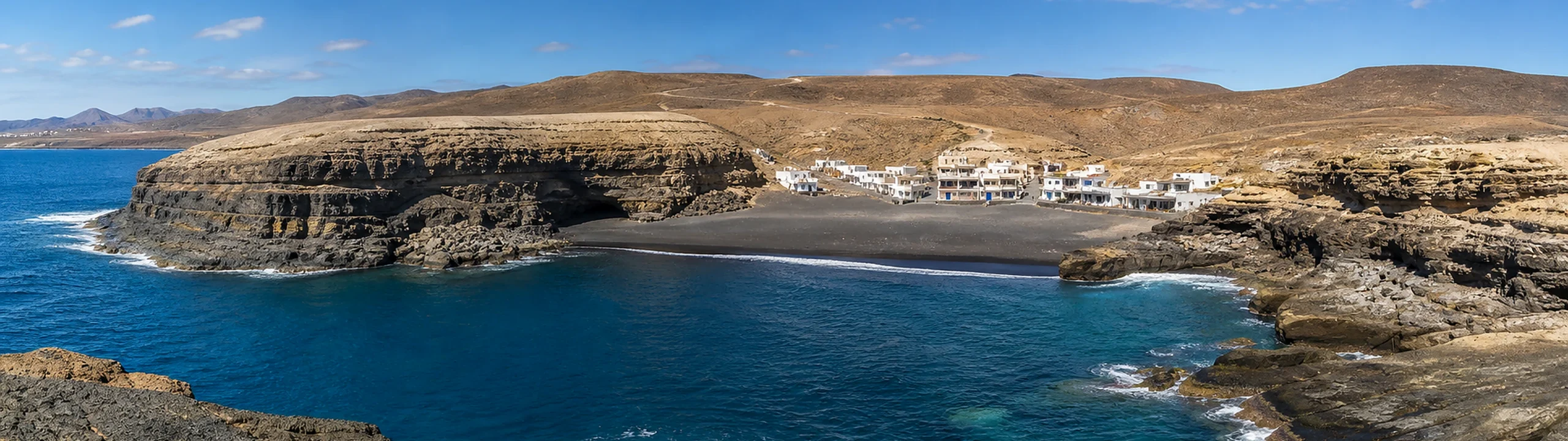 Panorámica nítida de Ajuy con su playa de arena negra, el pueblo y los acantilados