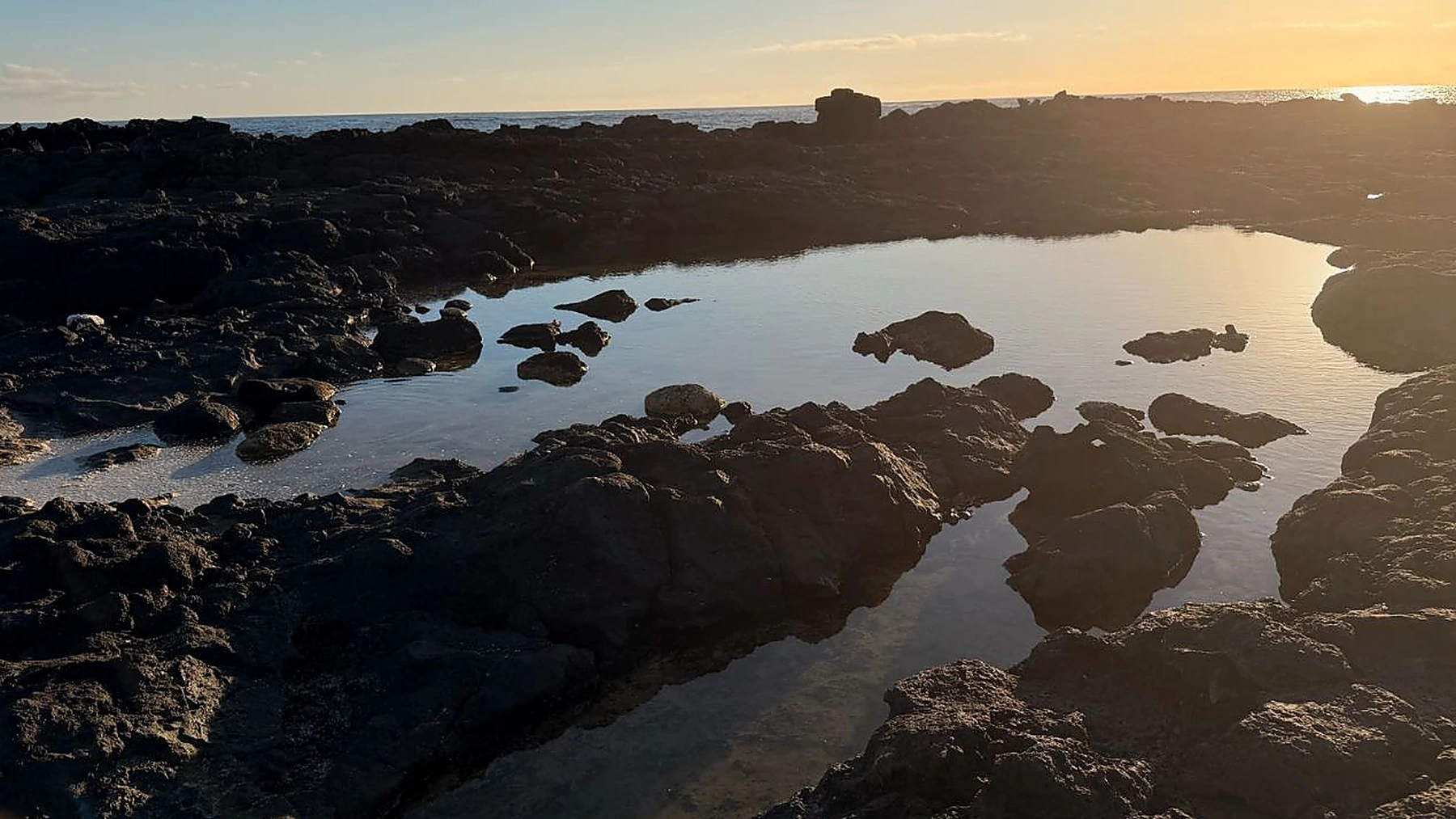 Piscinas naturales entre roca volcánica al atardecer en Los Charcos