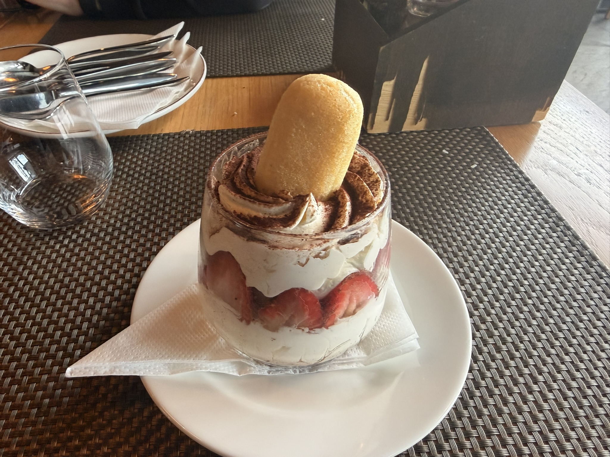 Postre en vaso con crema, fresas, cacao y bizcocho servido en Degenija