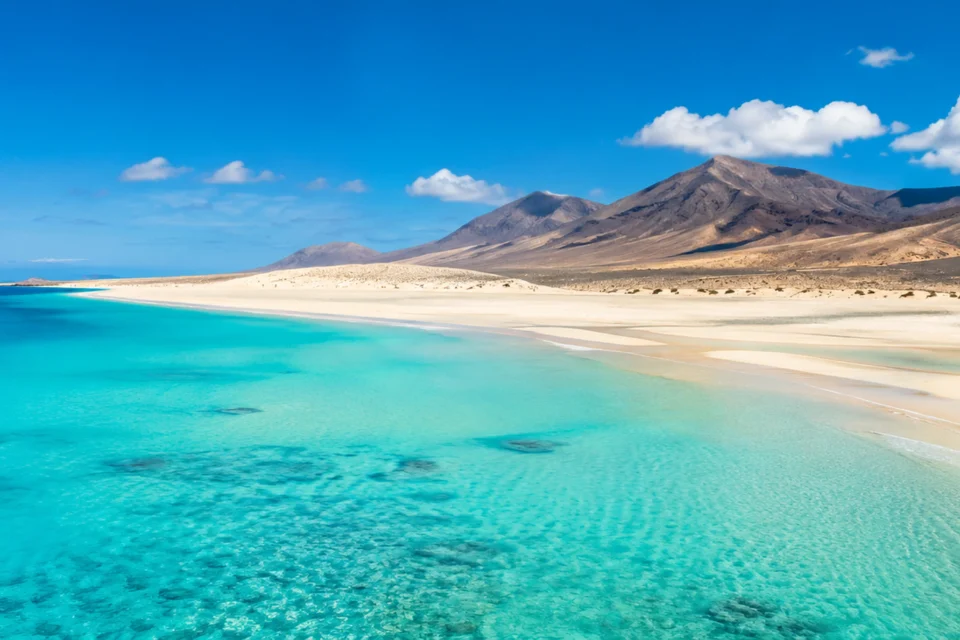 Panorámica de playa turquesa, arena clara y montañas de Fuerteventura para la cabecera