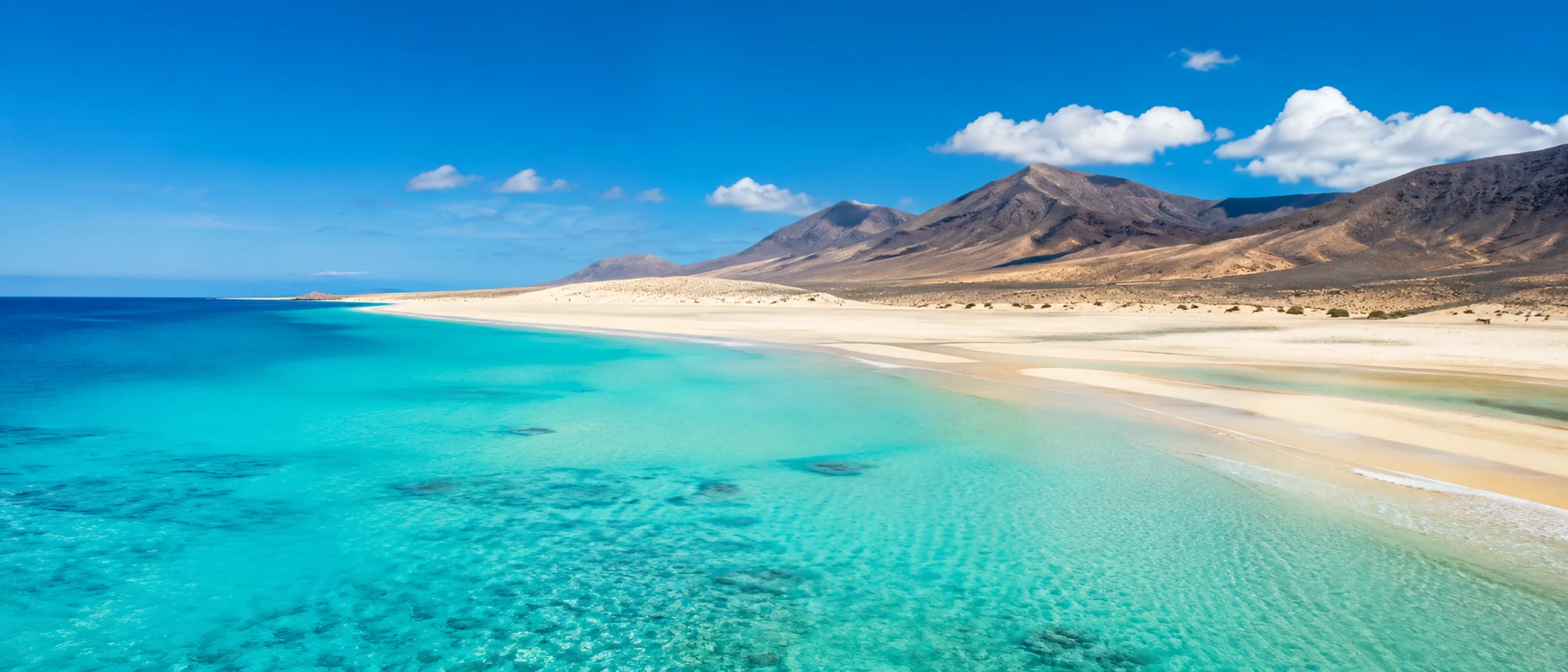 Panorámica de playa turquesa, arena clara y montañas de Fuerteventura para la cabecera