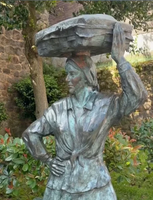 Escultura de La Lechera en Bermeo, centrada y elevada para mostrar bien la cara, sin marcos laterales ni franjas borrosas