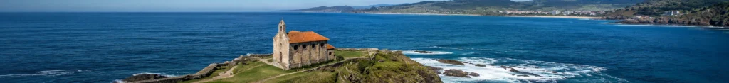 Ermita de Santa Catalina de Mundaka completa y alejada, con un suave degradado azul a la izquierda para mejorar la lectura del hero