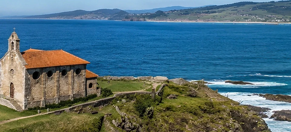 Ermita de Santa Catalina de Mundaka completa y alejada, con un suave degradado azul a la izquierda para mejorar la lectura del hero
