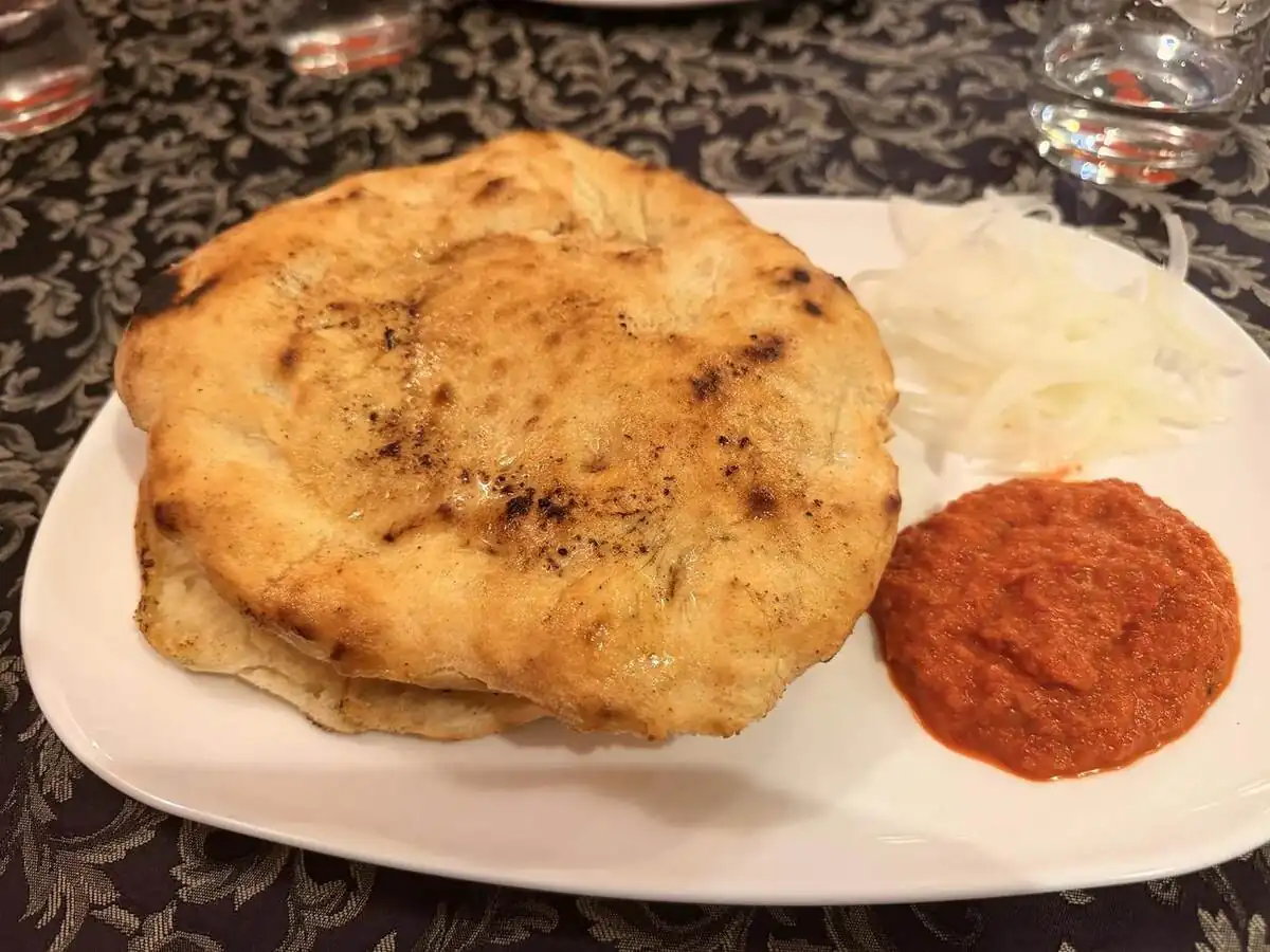 Ćevapi con pan, cebolla y ajvar servidos en Orfej de Pula