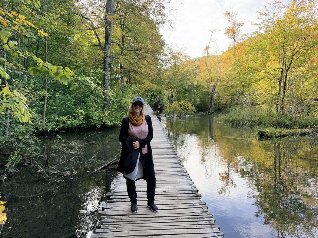 Alaitz caminando por una pasarela entre agua y bosque en los Lagos de Plitvice