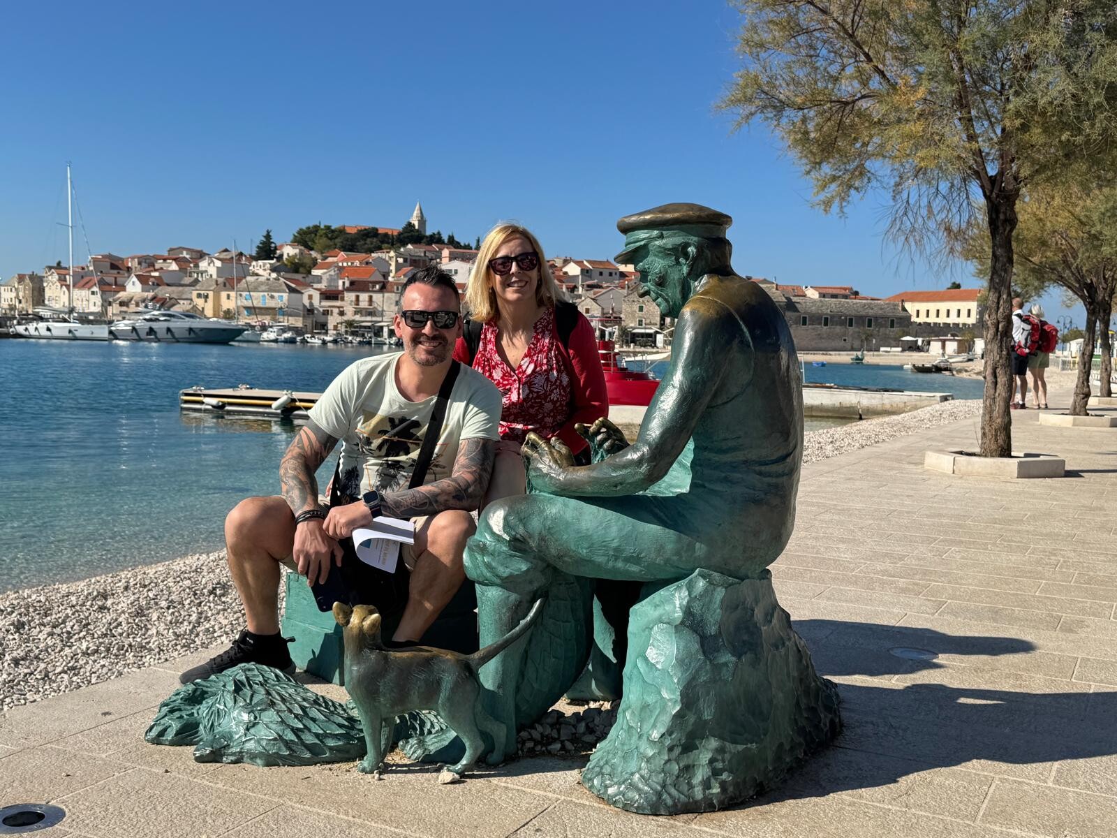 Txema y Alaitz junto a la escultura del pescador con Primošten al fondo