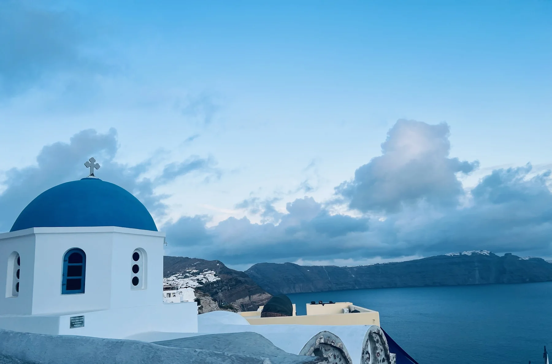 Iglesia de cúpula azul frente a la caldera en Oia