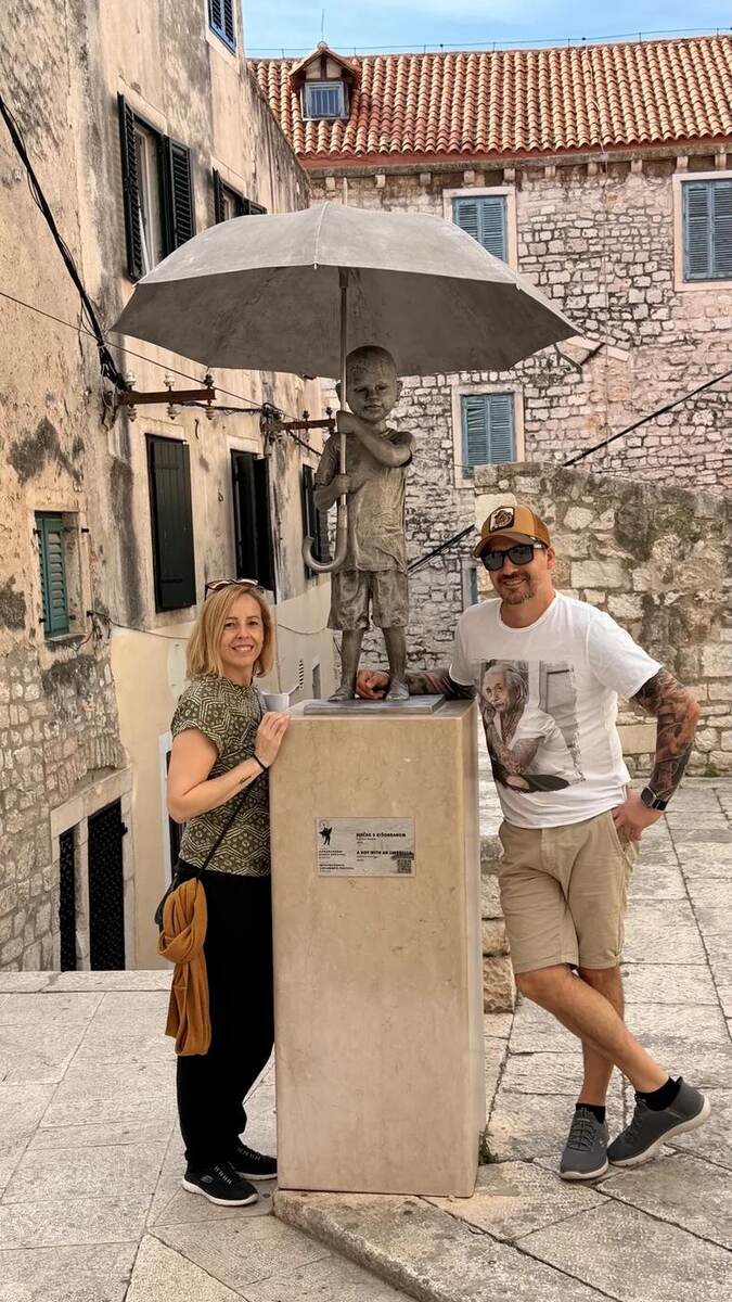 Txema y Alaitz junto a la escultura del niño con paraguas en Šibenik