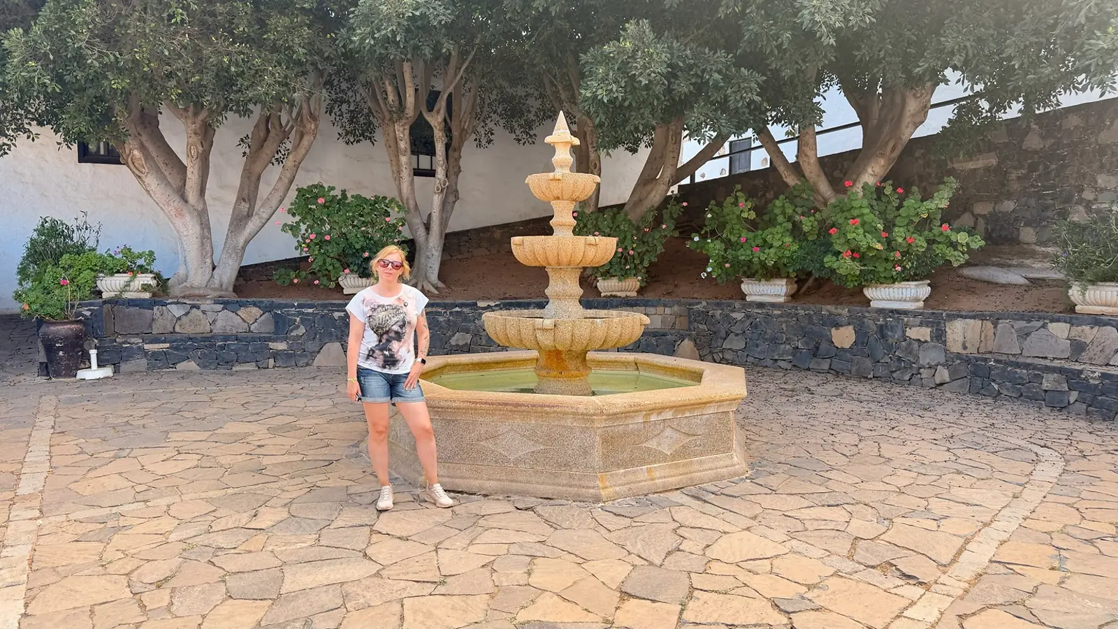 Fuente de piedra y vegetación en una plaza tranquila de Betancuria
