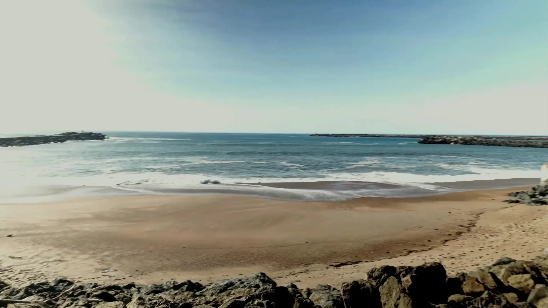 Arena, olas y espigón en la playa de Les Cavaliers