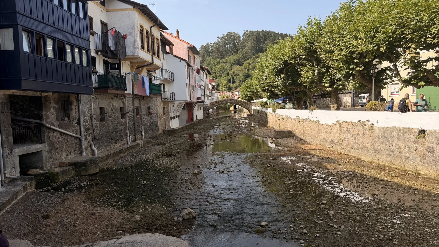 Ría de Ea en marea baja con casas y puente de piedra al fondo