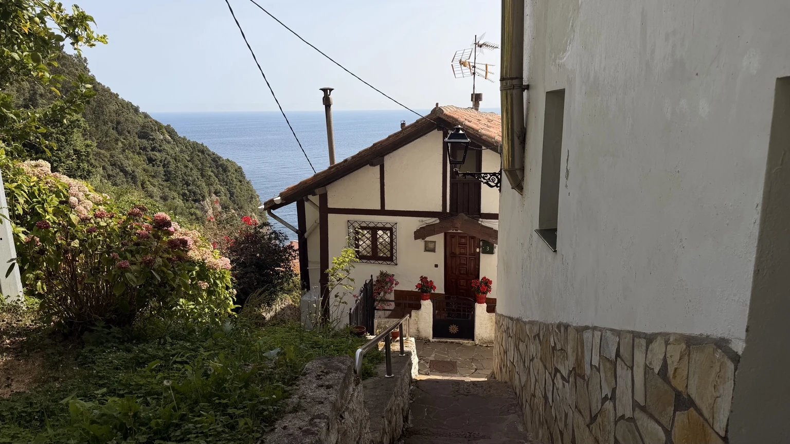 Calle escalonada de Elantxobe entre casas con el mar Cantábrico al fondo